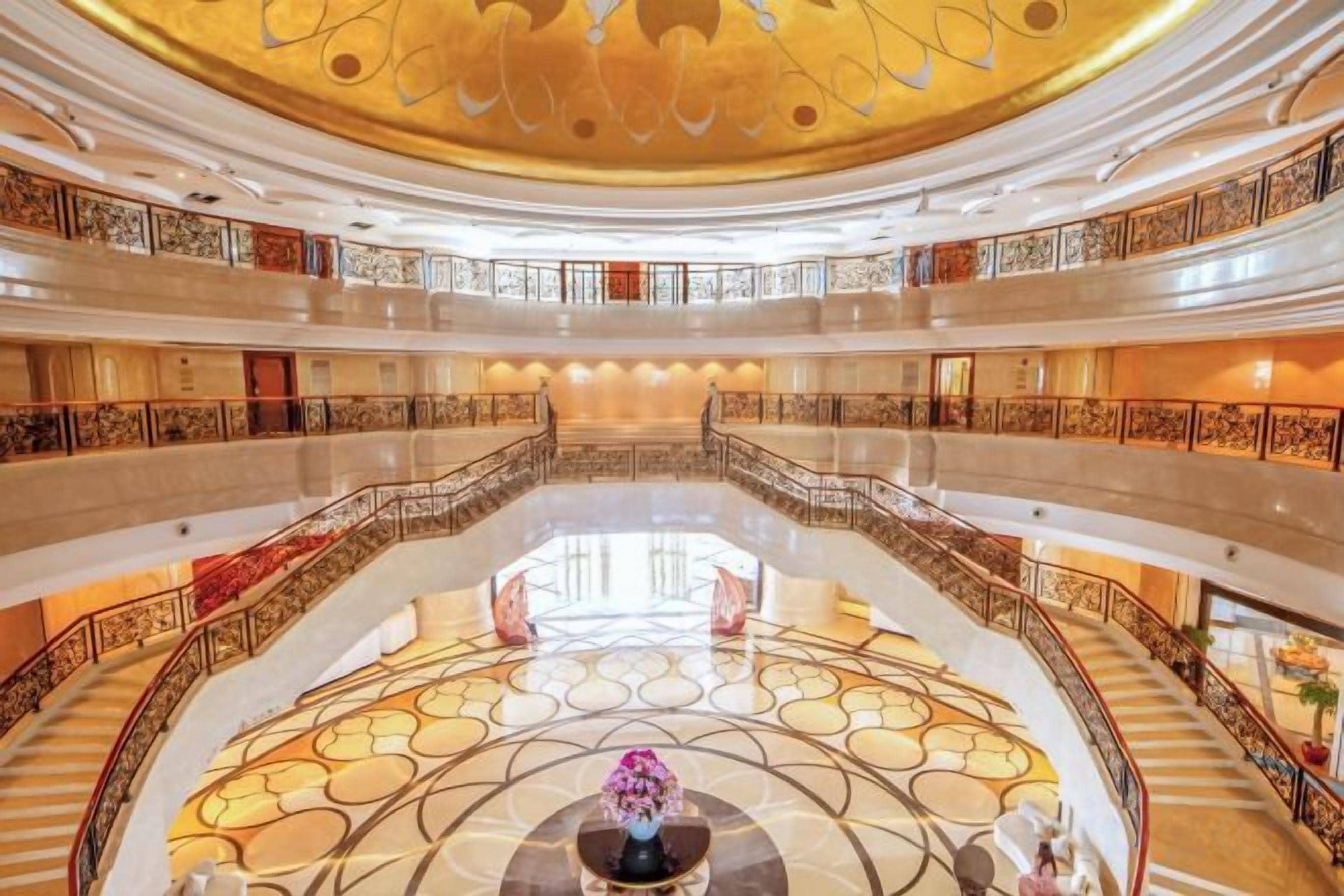 A multi-level atrium with a central open space, railings, and a decorative ceiling.
