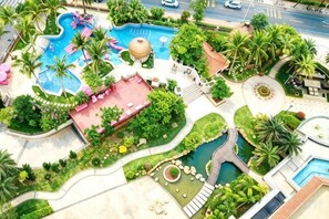 A resort with a swimming pool, palm trees, and a red-roofed building. - DoubleTree by Hilton Sanya Bay (Sanya)