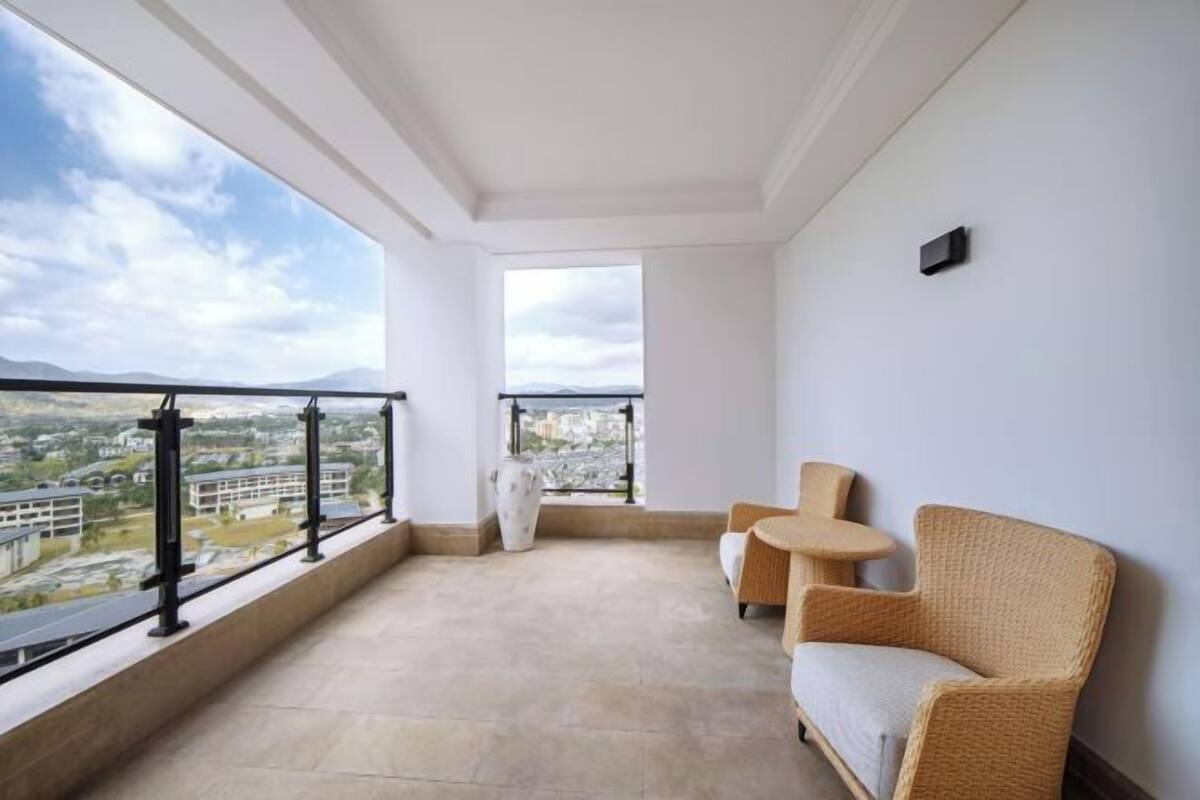 A balcony with a view of a cityscape, a wicker sofa, and a small round table.