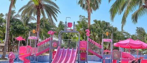 A water park with slides and a pool area, surrounded by palm trees.