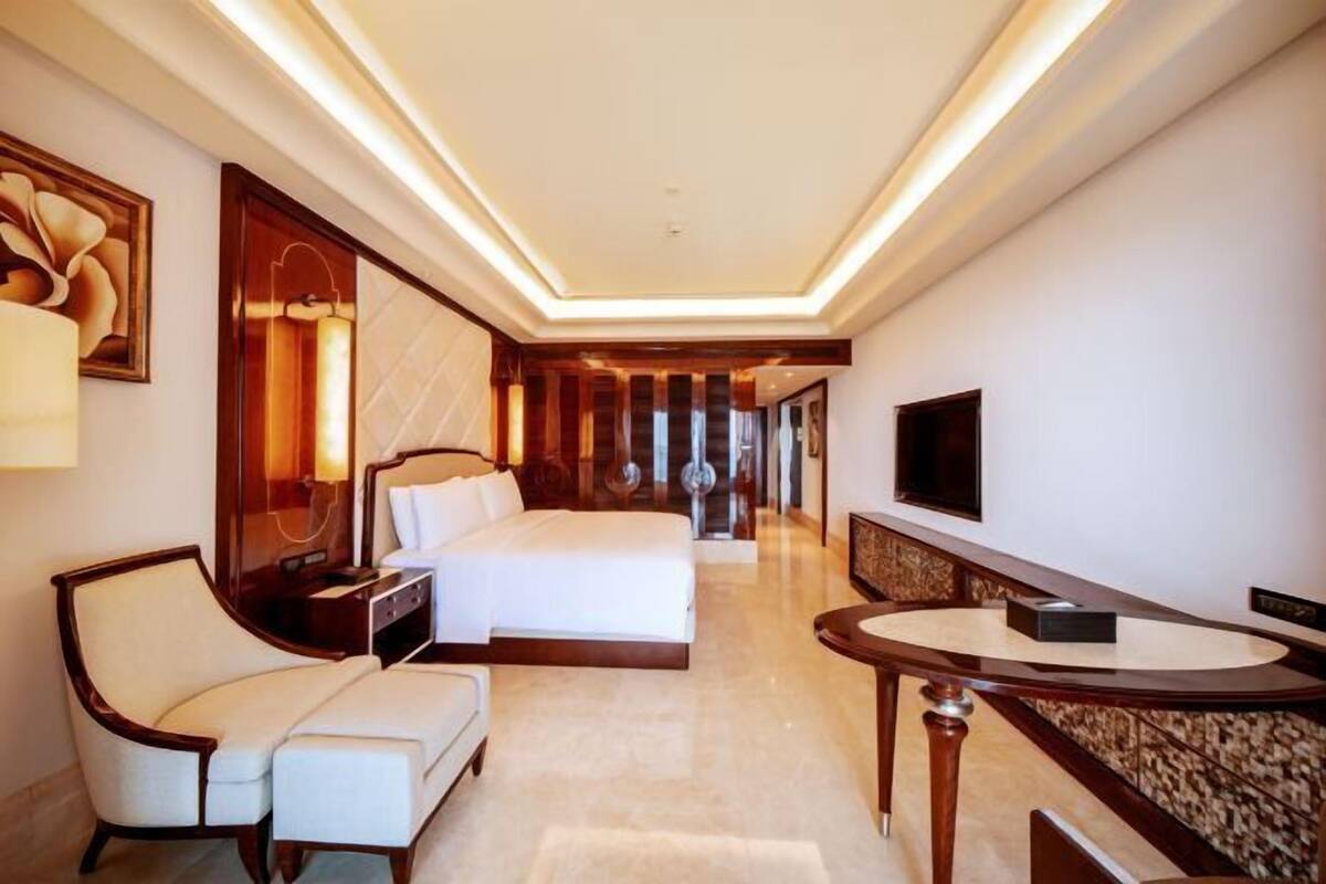 A hotel room with a bed, a seating area with a table, and a TV on the wall.