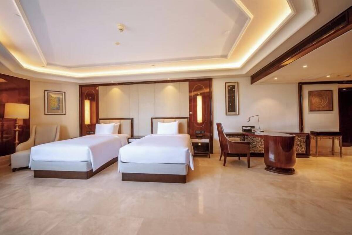 A hotel room with two beds, a desk, and a chair.