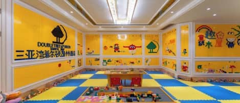 A playroom with colorful floor mats, a play table, and LEGO wall decorations.