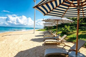 A beach with rows of sun loungers and striped umbrellas. - DoubleTree by Hilton Sanya Bay (Sanya)