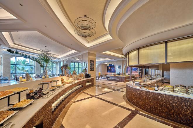 A spacious buffet area with a curved counter, large windows, and a modern ceiling design.