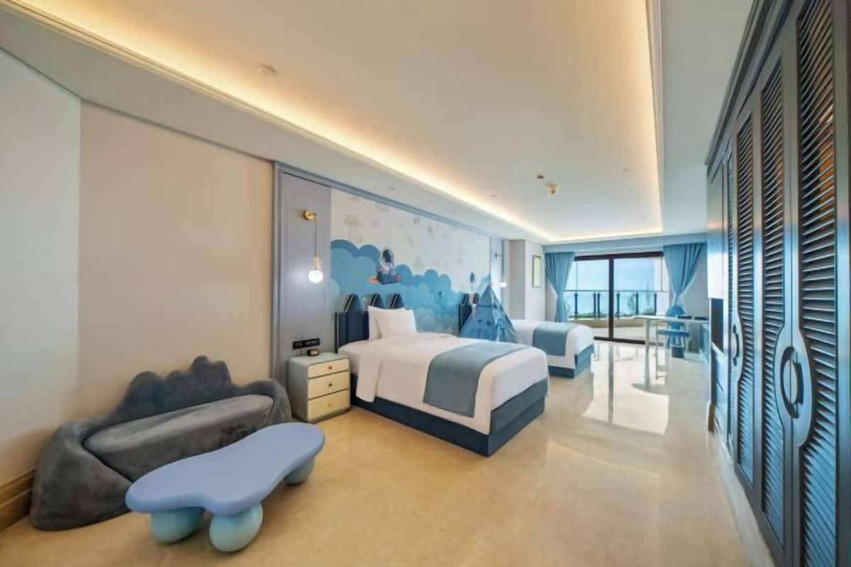 A modern hotel room with a large bed, a seating area, and a view of the outdoors.