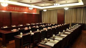 A conference room with long tables, chairs, nameplates, and a banner on the wall.