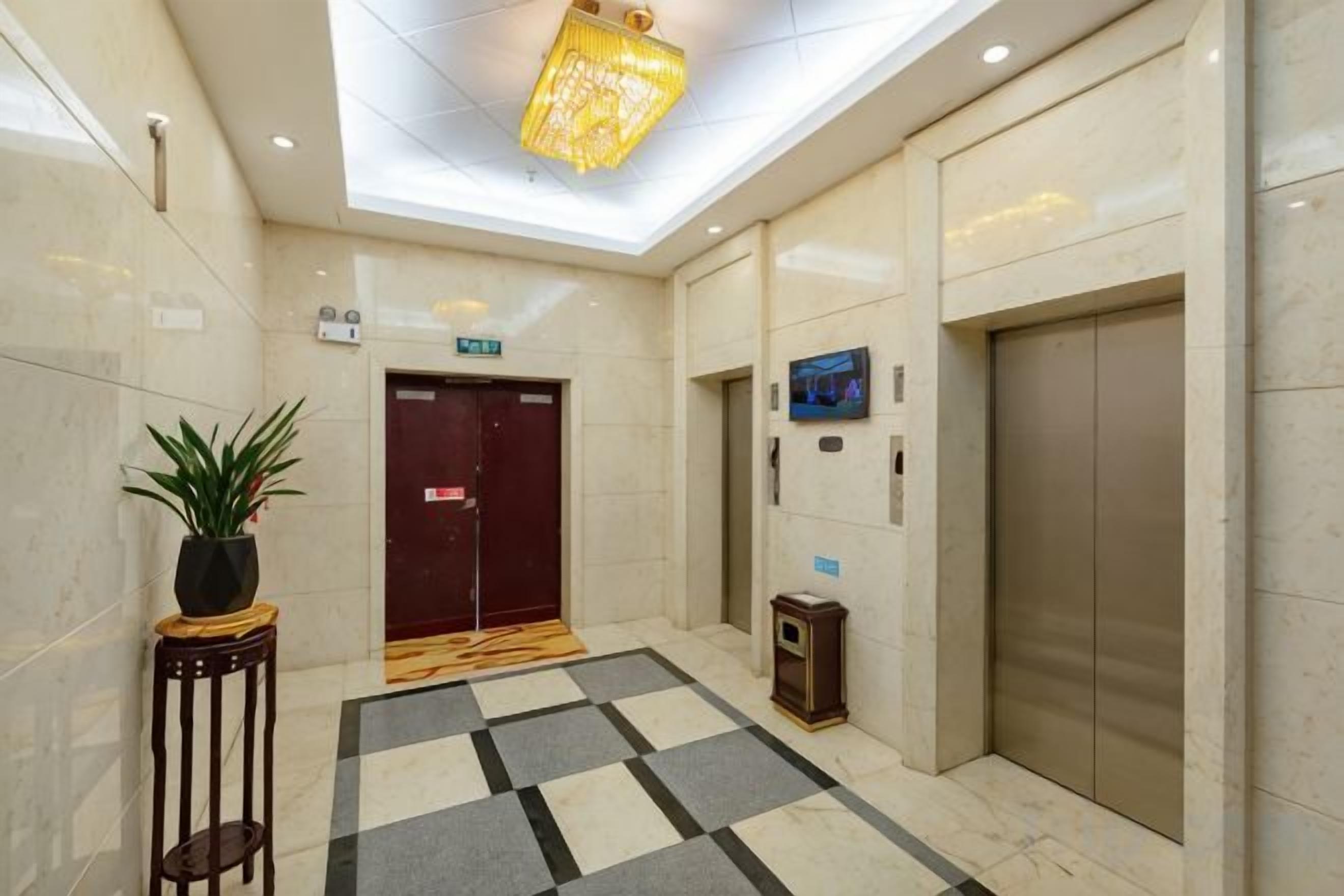 A hotel lobby with a check-in desk, a reception area, a staircase, and an elevator.