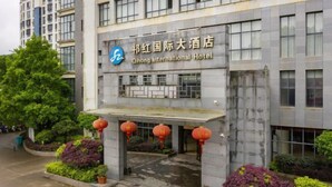 Ein Hotel Eingang mit einem Schild, auf dem 'Qing International Hotel' steht, und einer modernen Fassade.