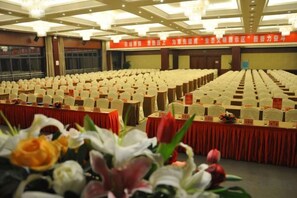 Ein Konferenzraum mit Reihen von Stühlen, Tischen mit Namensschildern und einer Blumendekoration im Vordergrund.