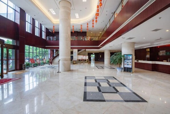 A spacious lobby with a checkered floor, large windows, and a reception desk.