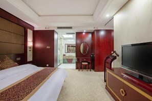 Ein Hotelzimmer mit Bett, Fernseher, Schreibtisch und Spiegel.
