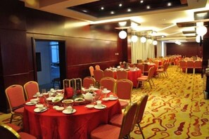 Une salle de conférence avec des tables rondes, des chaises et un sol recouvert de moquette.