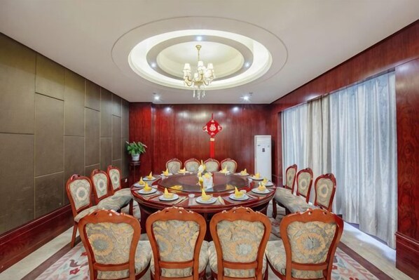 Uma sala de conferências com uma mesa redonda, cadeiras e um candelabro.