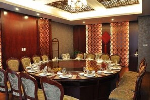 Une salle de conférence avec une table ronde, des chaises et un lustre.