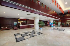 A hotel lobby with a reception desk, seating area, and decorative plants. - Qihong International Hotel (Qimen)