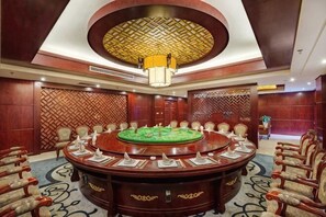 A conference room with a round table, chairs, and a patterned wall.