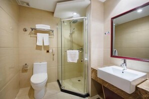 Ein modernes Badezimmer mit einer Duschkabine, einem weißen Waschbecken und einer Toilette.