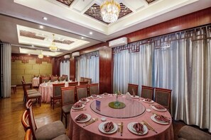 A dining area with round tables, chairs, and chandeliers. - Qihong International Hotel (Qimen)