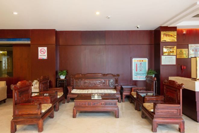 A lobby with wooden furniture, a reception desk, and a no-smoking sign.