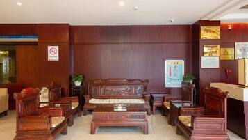 A lobby with wooden furniture, a reception desk, and a no-smoking sign.