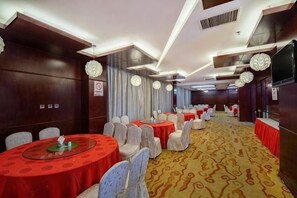 A banquet hall with round tables, chairs, and a patterned carpet. - Qihong International Hotel (Qimen)