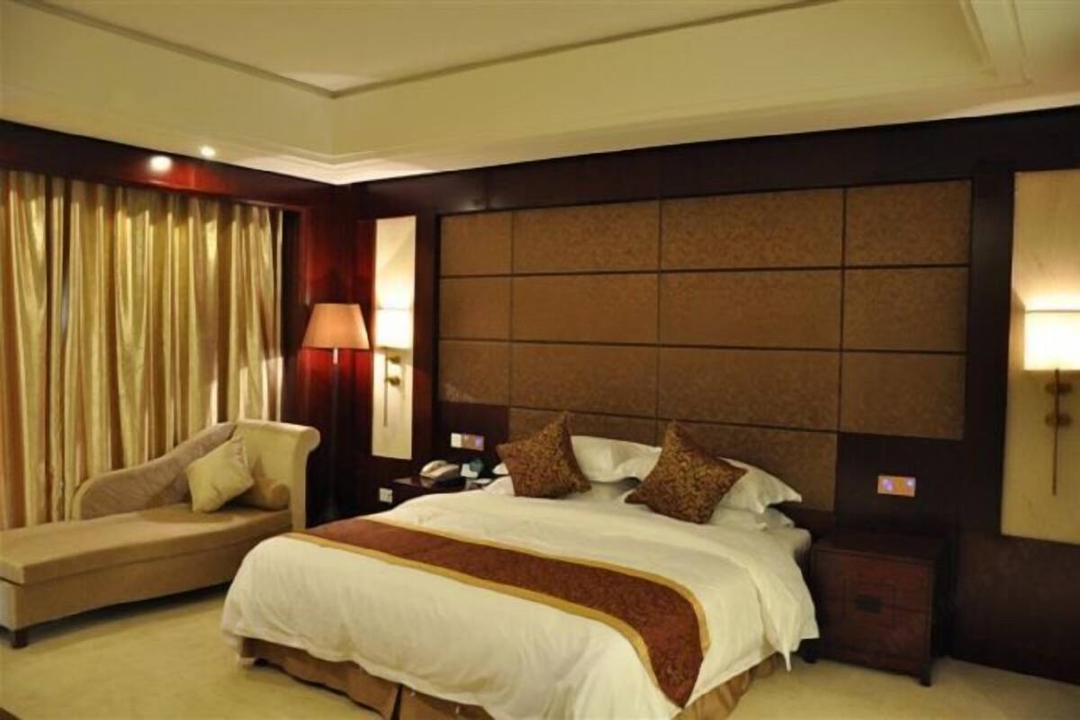 Ein Hotelzimmer mit einem großen Bett, einer Couch, einem Nachttisch und einer Lampe.