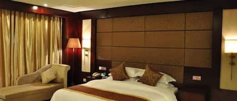 Une chambre d’hôtel avec un grand lit, un canapé, une table de chevet et une lampe.