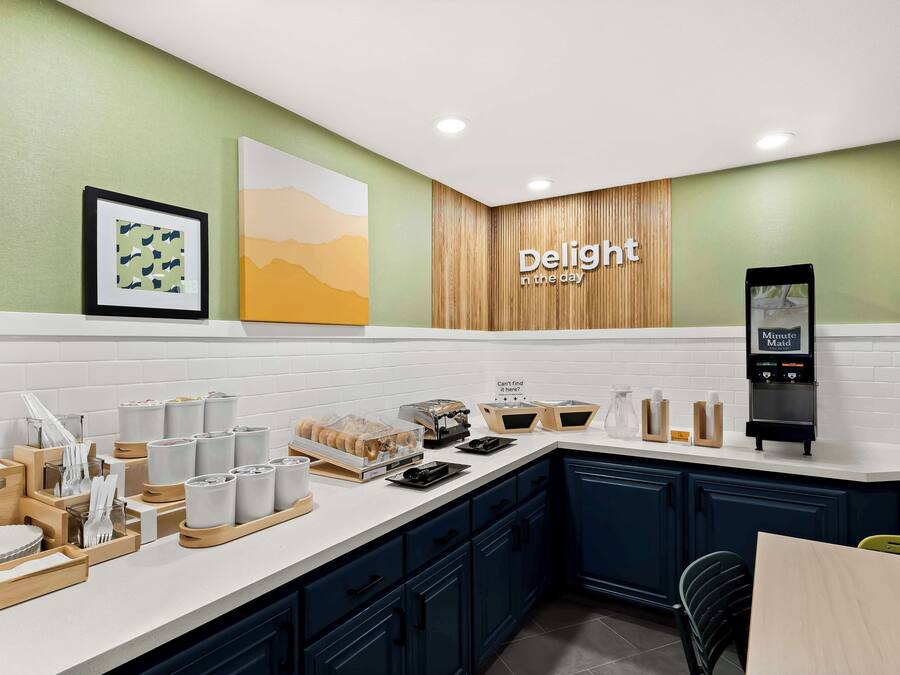 A modern kitchen with a white countertop, wooden cabinets, and a sign that reads "Delight in the day."