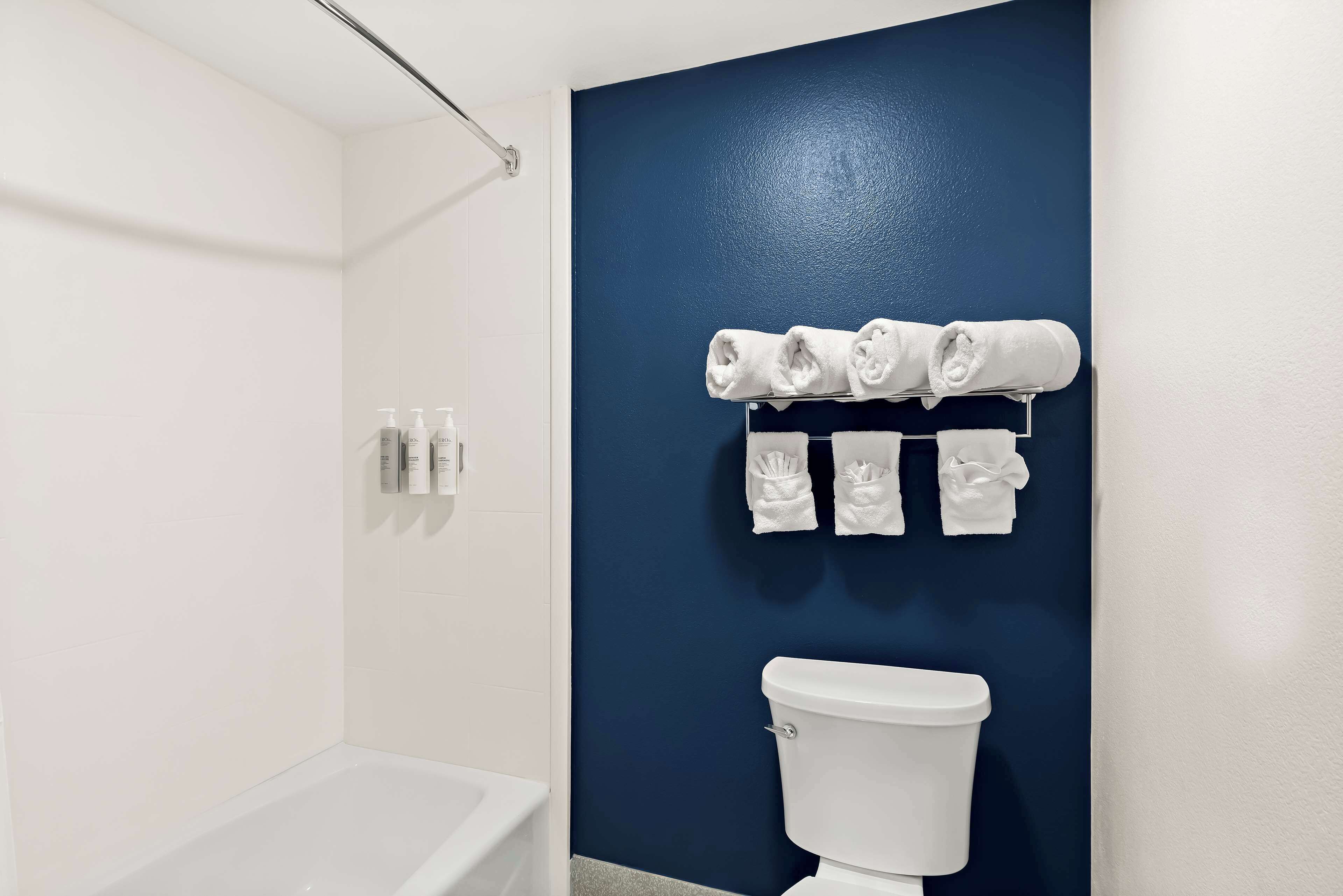 Une salle de bain avec une baignoire blanche, des toilettes et un porte-serviettes sur lequel sont soigneusement pliées des serviettes.