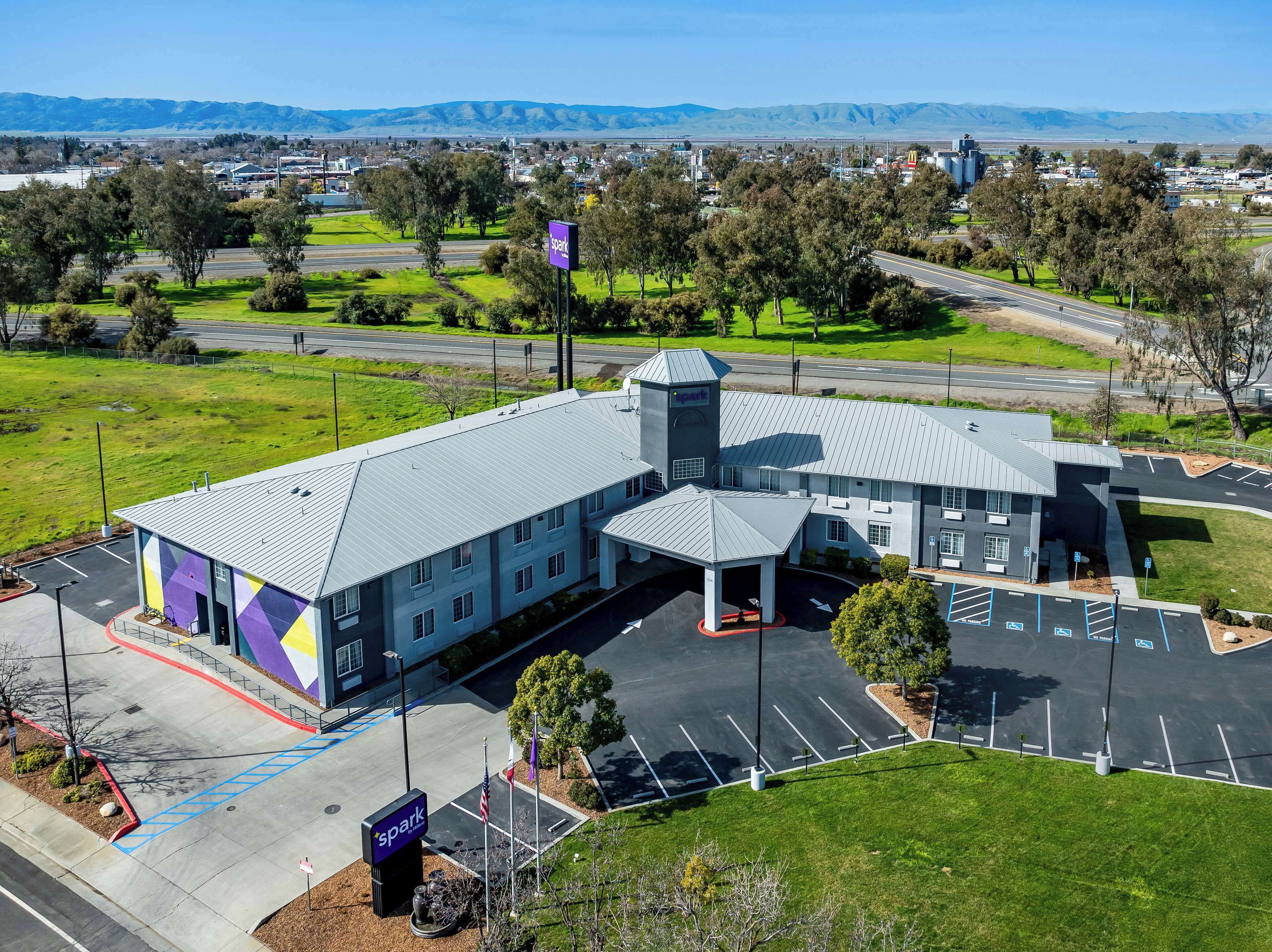 A modern building with a parking lot and a view of distant mountains.