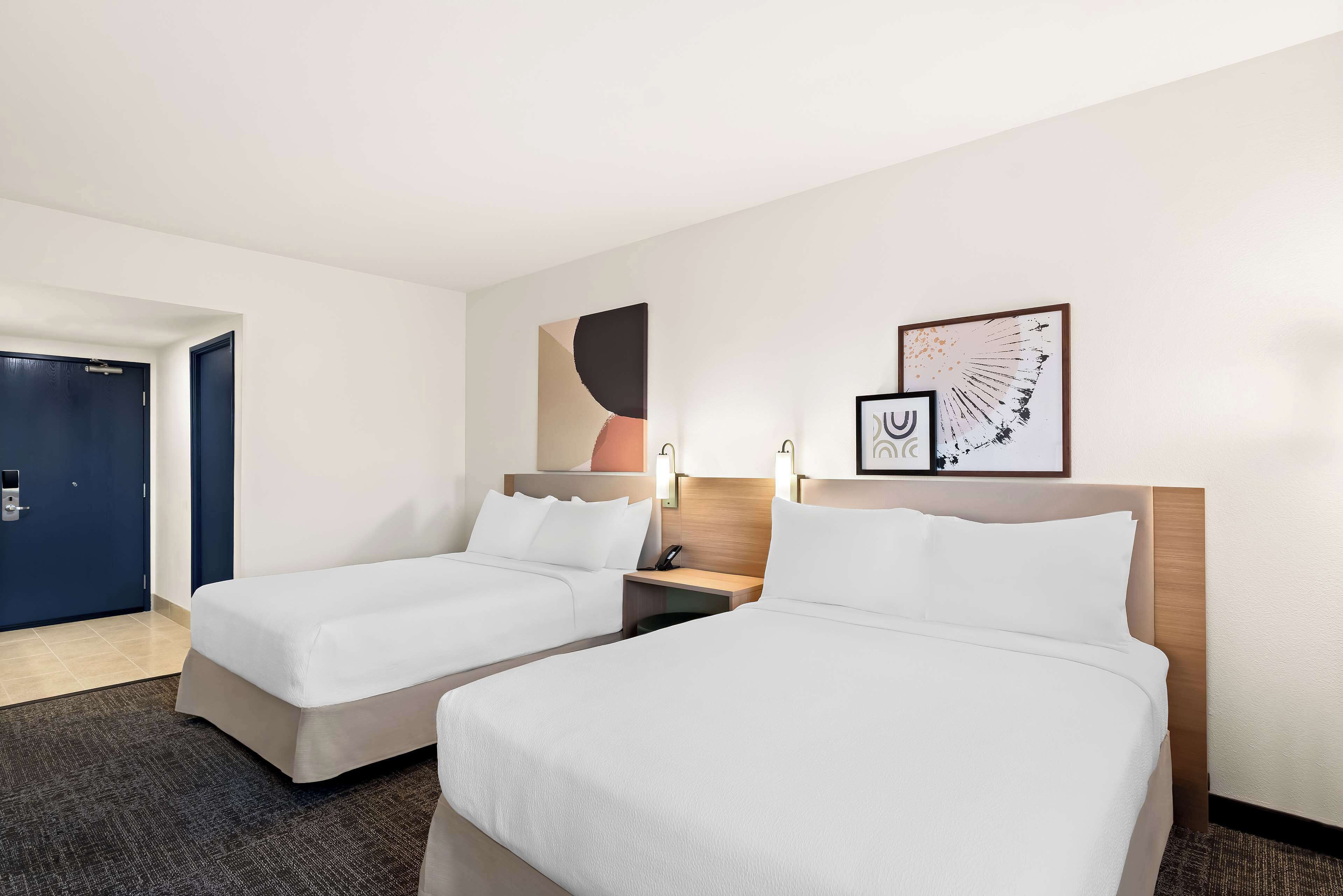 Ein Hotelzimmer mit zwei Betten, einer Tür und Bildern an der Wand.