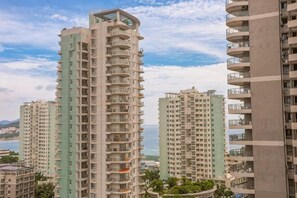 Edificios residenciales de gran altura con balcones, un cielo despejado y una masa de agua distante.