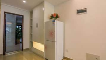 A modern kitchen with white cabinets, a built-in refrigerator, and a potted plant on the counter.