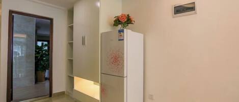 A modern kitchen with white cabinets, a built-in refrigerator, and a potted plant on the counter.