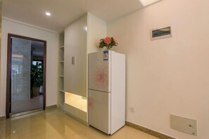 A modern kitchen with white cabinets, a built-in refrigerator, and a potted plant on the counter. - Sanya Dadonghai Jiahe Apartment (Summer Department Store) (Sanya)
