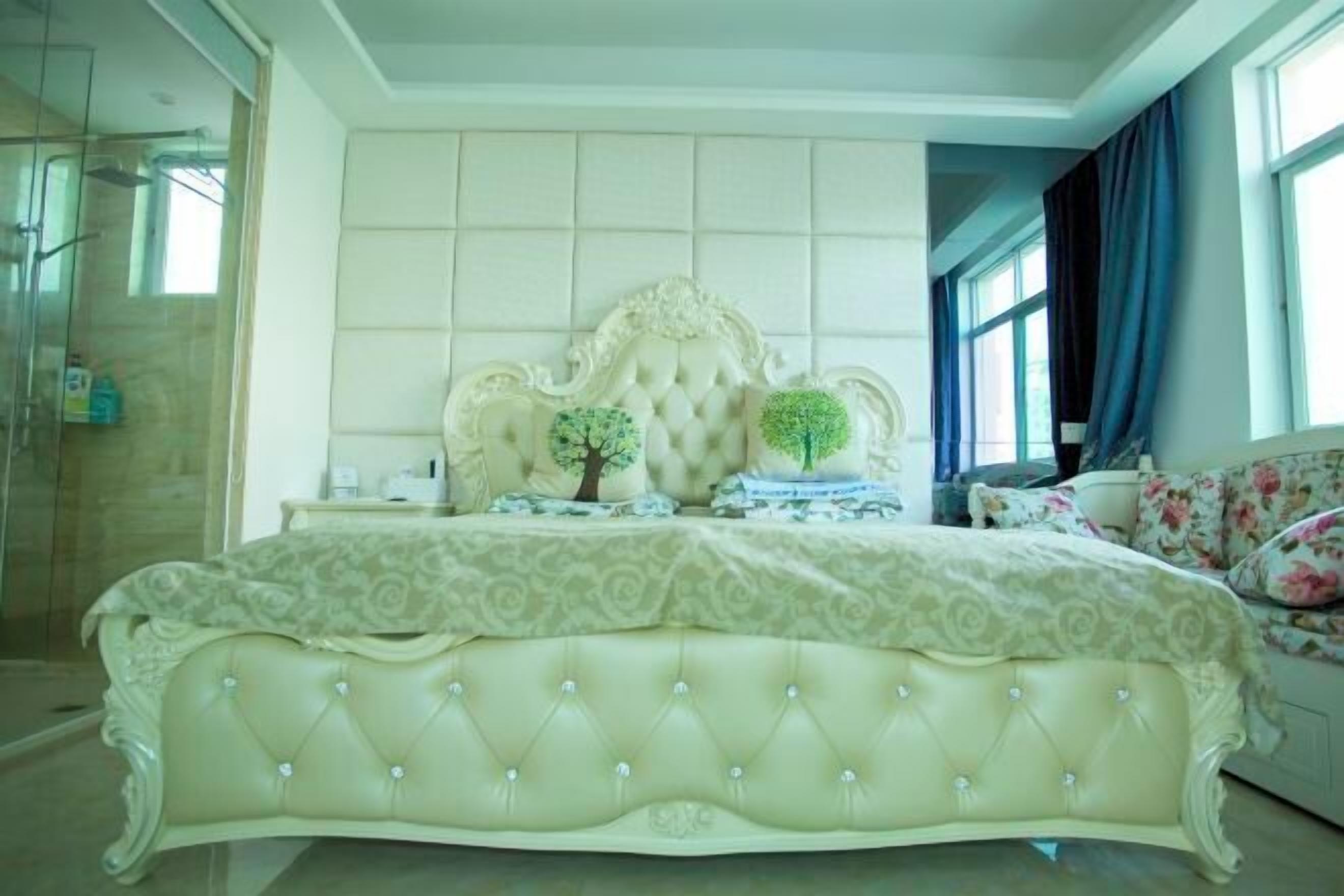 A luxurious bedroom with a tufted headboard, a decorative mirror, and a floral-patterned sofa.