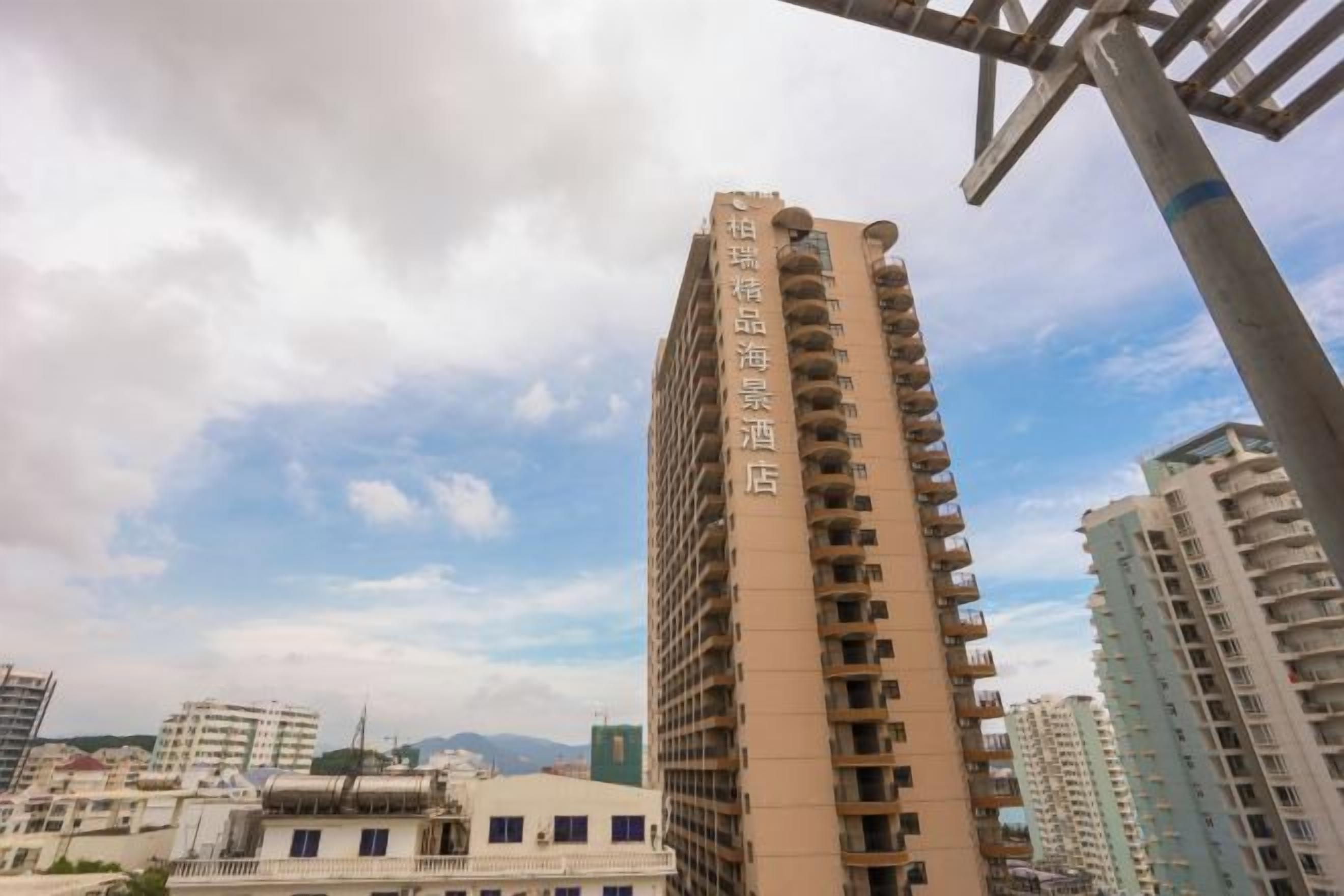 Un edificio alto con varios balcones, rodeado de otros edificios.