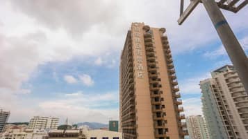 A high-rise building with multiple balconies, surrounded by other buildings.