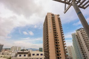 Un edificio alto con varios balcones, rodeado de otros edificios.