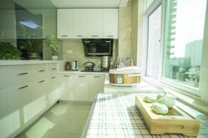 A modern kitchen with white cabinets, a microwave, a kettle, and a wooden cutting board with bowls. - Sanya Dadonghai Jiahe Apartment (Summer Department Store) (Sanya)