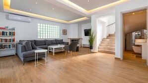 Ein modernes Wohnzimmer mit grauem Sofa, einem Couchtisch, einem Bücherregal und einem Kamin.