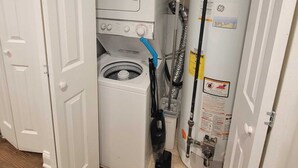 A compact laundry room with a front-loading washer and dryer, a water heater, and visible plumbing. - Cozy 2-bedroom apartment in welcoming Chicago in the Wicker Park area (Chicago)