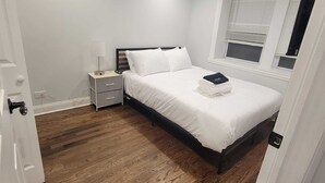 A bedroom with a bed, a nightstand, a lamp, and a window with blinds. - Cozy 2-bedroom apartment in welcoming Chicago in the Wicker Park area (Chicago)