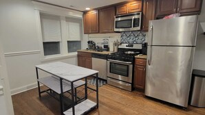 A modern kitchen with wooden cabinets, stainless steel appliances, and a marble countertop. - Cozy 2-bedroom apartment in welcoming Chicago in the Wicker Park area (Chicago)
