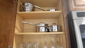 A kitchen cabinet with shelves holding pots, pans, and wine glasses. - Cozy 2-bedroom apartment in welcoming Chicago in the Wicker Park area (Chicago)