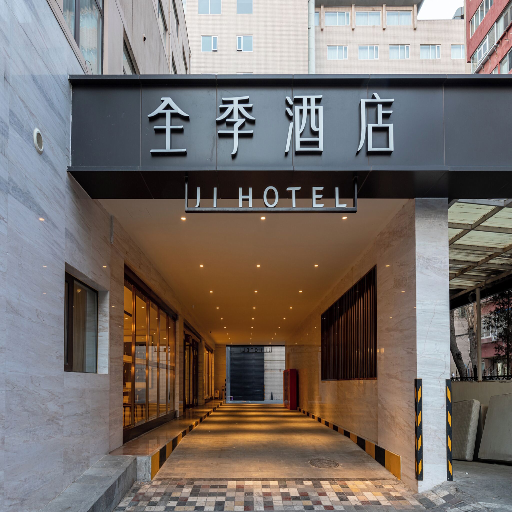 A hotel entrance with a sign reading 'JI HOTEL' in both Chinese and English.