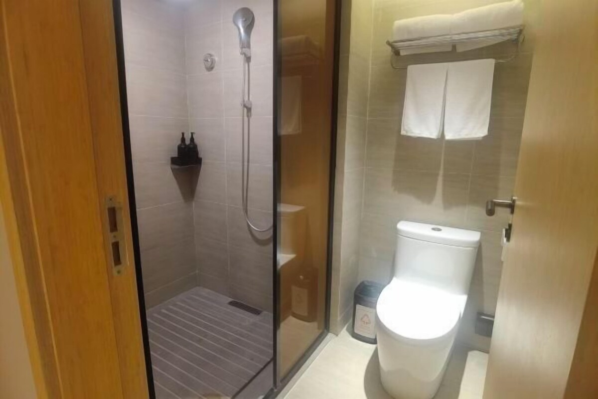 A bathroom with a glass-enclosed shower, a toilet, and a sink.