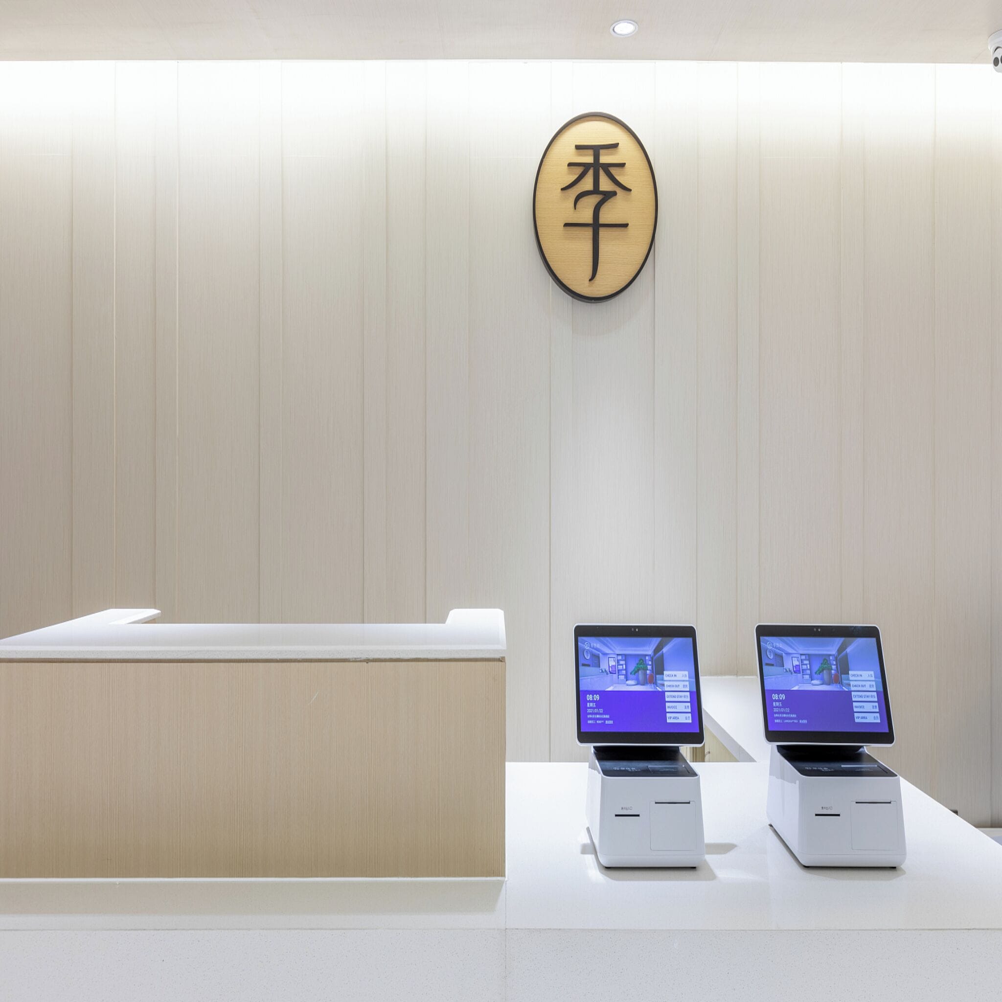 A reception desk with a wooden sign, two digital displays, and a white counter.