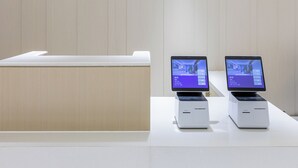 A reception desk with a wooden sign, two digital displays, and a white counter. - Ji Hotel (Beijing)